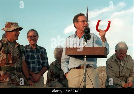 President George Bush holds up a horseshoe as he addresses the Marines and Seabees at a desert encampment. The president and his wife are paying Thanksgiving Day visits to U.S. troops who are in Saudi Arabia for Operation Desert Shield. Subject Operation/Series: DESERT SHIELD Country: Saudi Arabia (SAU) Stock Photo