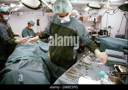 An assistant gets a pair of forceps for the doctor as a surgical team ...