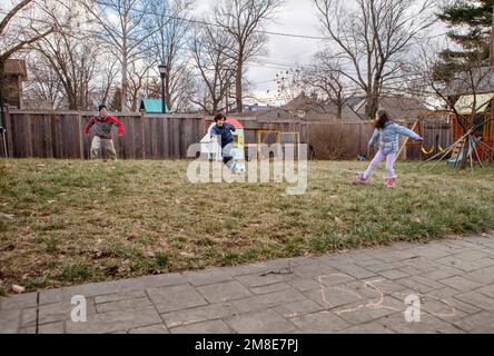 A boy plays soccer with his family in suburban backyard in winter Stock Photo
