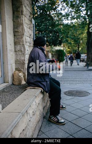 Sad homeless man begs for money at the street. Stock Photo