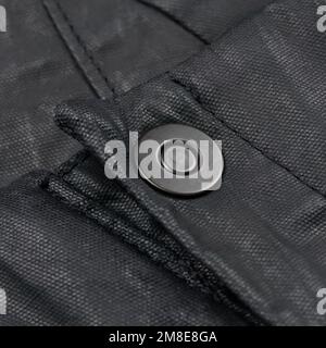 Metal fastener on avant-garde black waxed pants Stock Photo