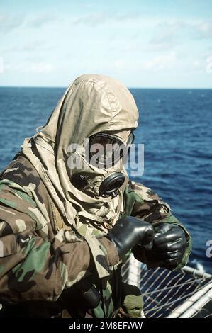 A member of Weapons Co., 1ST Bn., 6th Marines, assigned to Regimental Landing Team 4, tries on nuclear-biological-chemical warfare gear aboard the amphibious transport dock USS DUBUQUE (LPD-8). The vessel is deploying to the Middle East to take part in Operation Desert Shield. Subject Operation/Series: DESERT SHIELD Base: USS Dubuque (LPD 8) Country: Atlantic Ocean (AOC) Stock Photo