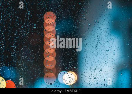 Raindrops on car windshield during night driving on a rainy evening Stock Photo