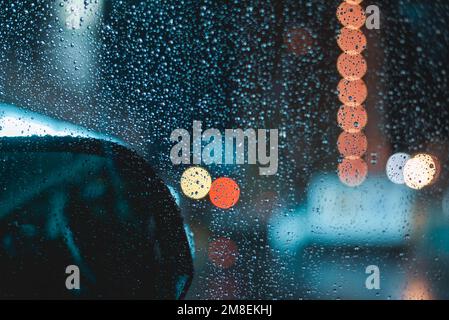 Raindrops on car windshield during night driving on a rainy evening Stock Photo