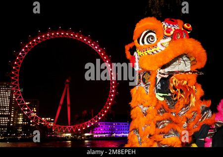 London, Britain. 13th Jan, 2023. Traditional Chinese lion dancers perform in front of the London Eye which is lit up in red to celebrate the upcoming Chinese New Year in London, Britain, Jan. 13, 2023. Credit: Li Ying/Xinhua/Alamy Live News Stock Photo