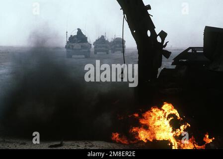 Armored personnel carriers of the 7th Brigade Royal Scots, 1ST United Kingdom Armored Division, pass a burning Iraqi anti-tank vehicle while advancing east into Kuwait from southern Iraq during Operation Desert Storm. Subject Operation/Series: DESERT STORM Country: Kuwait(KWT) Stock Photo