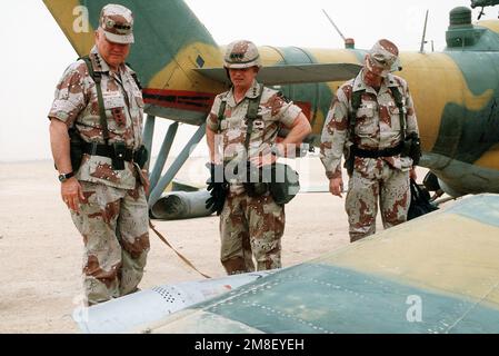 GEN. Norman Schwarzkopf, commander-in-chief, U.S. Central Command, and LT. GEN. Gary Luck, commander, XVIII Airborne Corps, inspect a weapons pod and auxiliary wing of an Iraqi MIL Mi-24 Hind helicopter captured during Operation Desert Storm. The aircraft is on the airfield at the XVIII Airborne Corps base of operations at Rahfa Airport.. Subject Operation/Series: DESERT STORM Country: Saudi Arabia(SAU) Stock Photo