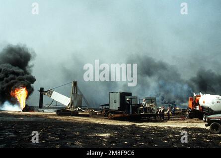 Firefighters from the Boots and Coots Oil Well Firefighting Company prepare to position a cap on a blazing well in the aftermath of Operation Desert Storm. The well, situated in the Ahman Oil Fields, is one of many set afire by Iraqi forces prior to their retreat from Kuwait.. Subject Operation/Series: DESERT STORM Base: Ahman Oil Fields Country: Kuwait(KWT) Stock Photo