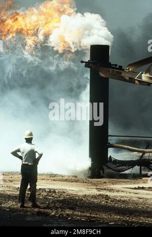 Firefighters from the Boots and Coots Oil Well Firefighting Company use a crane to cap a blazing well in the aftermath of Operation Desert Storm. The well, situated in the Ahman Oil Fields, is one of many set afire by Iraqi forces prior to their retreat from Kuwait.. Subject Operation/Series: DESERT STORM Base: Ahman Oil Fields Country: Kuwait(KWT) Stock Photo