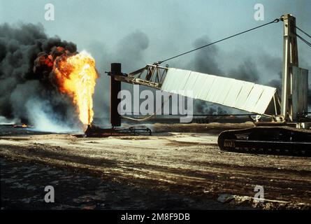 Firefighters from the Boots and Coots Oil Well Firefighting Company prepare to position a cap on a blazing well in the aftermath of Operation Desert Storm. The well, situated in the Ahman Oil Fields, is one of many set afire by Iraqi forces prior to their retreat from Kuwait.. Subject Operation/Series: DESERT STORM Base: Ahman Oil Fields Country: Kuwait(KWT) Stock Photo