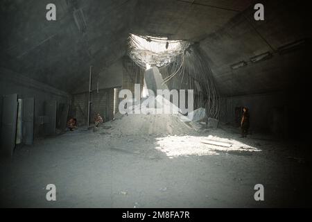 U.S. Soldiers inspect a hardened aircraft shelter damaged by Coalition bombing during Operation Desert Storm. Iraqi forces held the air base during their occupation of Kuwait.. Subject Operation/Series: DESERT STORM Base: Ali Al Salem Air Base Country: Kuwait(KWT) Stock Photo