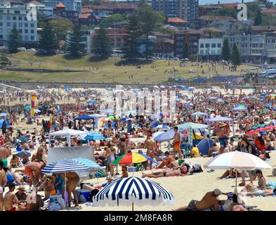 Christmas Day on Bondi Beach is a hot, sunny fun experience with many beachgoers wearing red and green swimmers or bathers and Santa hats Stock Photo