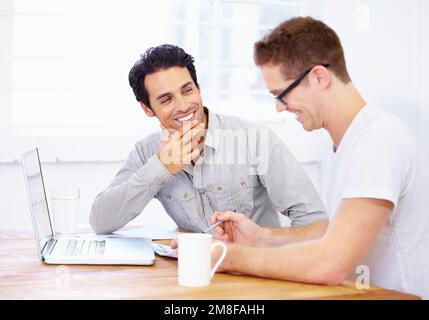 Talking business. two happy-looking business professionals having a conversation over a laptop. Stock Photo