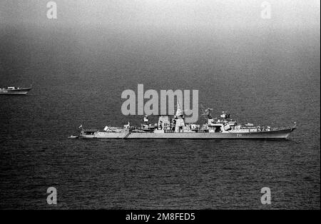 A starboard beam view of the Soviet Kara class guided missile cruiser Kerch at anchor. The starboard bow of a Soviet Krivak II class frigate is in the background, at left. Country: Mediterranean Sea(MED) Stock Photo