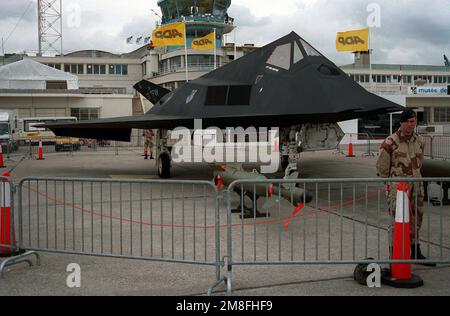 An F-117A Stealth Fighter aircraft stands on the flight line as part of a static display at the Paris Air Show. A laser-guided bomb is on display in front of the aircraft.. Base: Paris Country: France(FRA) Stock Photo