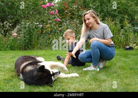 A boy and a girl with a dog on a green lawn Stock Photo