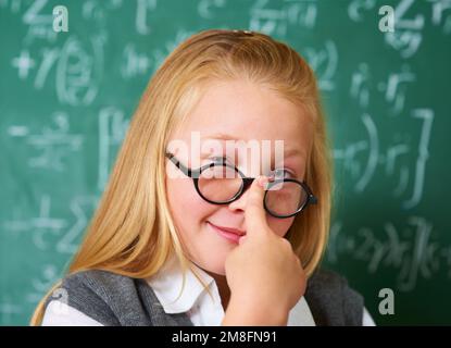 Shes got the right attitude. Portrait of a cute blonde girl putting her glasses on in class. Stock Photo