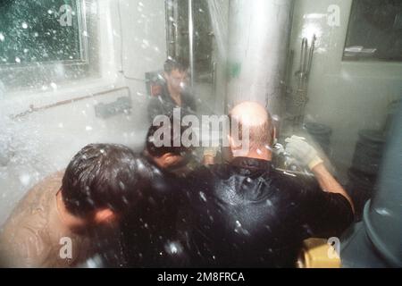 Crew members attach a temporary patch to a leaking pipe in a submarine