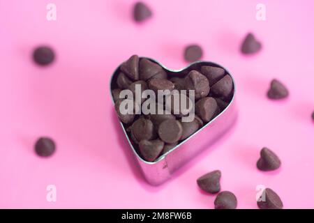 choco chips with heart cutter on pink background. Flat lay. Love concept. valentine's day concept. Stock Photo