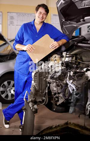 Hes a great mechanic. Portrait of a male mechanic with a clipboard in his hands while working on a car. Stock Photo
