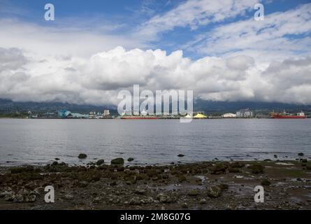 North Vancouver - mountains, bay, Cargo warehouse - industrial port, cargo ship. beautiful clouds and the sea. Travel in the summer. Stock Photo