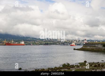 North Vancouver - mountains, bay, Cargo warehouse - industrial port, cargo ship. beautiful clouds and the sea. Travel in the summer. Stock Photo