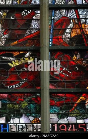 The army of righteousness slays the dragons of mischief: detail of vibrant stained glass, inspired by biblical Book of Revelation, in Liberation Window in the Oude Kerk or Old Church in Delft, South Holland, Netherlands.  The 1950s window celebrates the withdrawal of German troops from the city in May 1945, at the end of World War II, following five years of Nazi occupation. Stock Photo