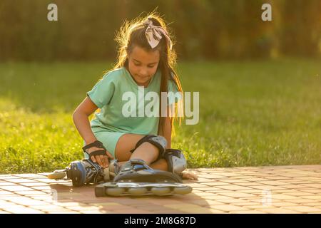 Little girl learns to roller skate and falls. Stock Photo