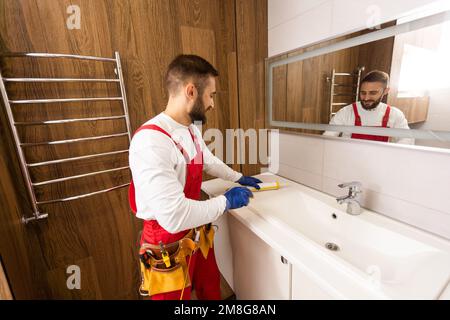 a worker installs a wash basin in a bathroom. Stock Photo