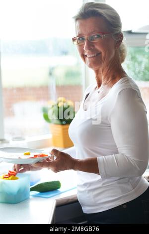 Healthy snacks. Portrait of a senior woman making herself a healthy snack for lunch. Stock Photo
