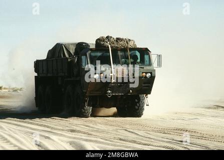 A M977 heavy expanded mobility tactical truck (HEMTT) travels with a convoy on a desert road during Operation Desert Shield. Subject Operation/Series: DESERT SHIELD Country: Saudi Arabia(SAU) Stock Photo