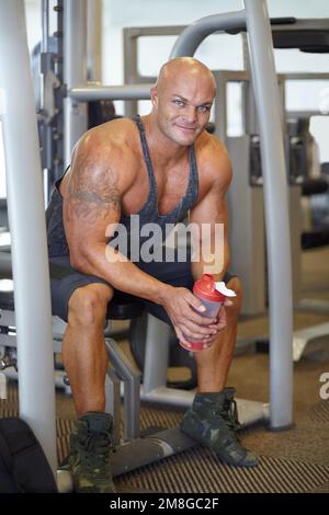 Shirtless young man drinking protein shake in gym Photograph by