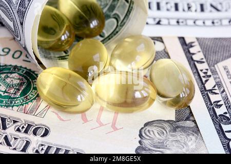 Gel capsules pouring out of rolled dollar bills - symbol of increasing heath care costs Stock Photo