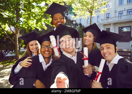 Ex student takes selfie with his classmates after agraduation ceremony. Stock Photo