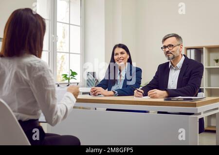 Two human resources workers listen as female job candidate talks about her work experience. Stock Photo