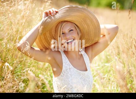 Shes as natural as the world around her. a beautiful young woman in a sunhat walking through tall grass. Stock Photo