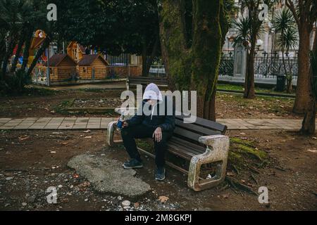 Homeless man or alcoholic sleeping on bench. Poor man on city street. Stock Photo