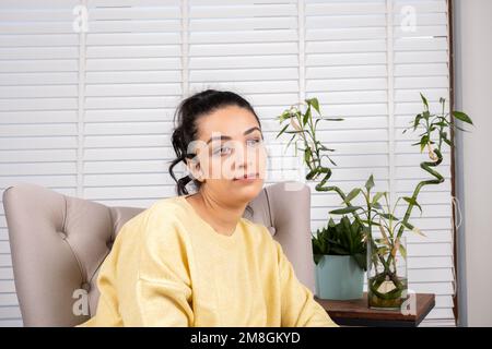 Upset woman. Lost in thoughts. Sitting alone on armchair. Received bad news concept. Anxiety, personal problems. Unhappy depressed bored young girl. Stock Photo