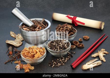 Ancient traditional Chinese herbal plant medicine concept. Preparation of herbs, spice for natural medicinal treatment with scroll for prescription. Stock Photo