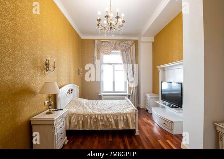 large bright bedroom in yellow tones with huge bed. Stock Photo