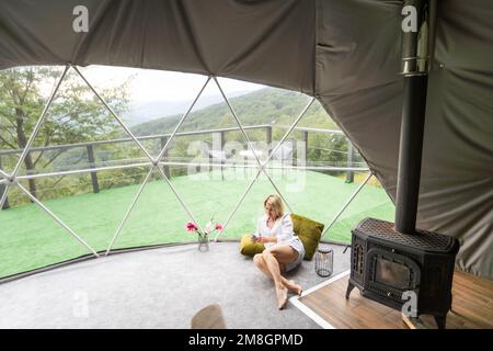 A woman sits in a geo dome glamping tent and meditates, does pranayamas,  looks at the winter snow-covered nature. Rear view Stock Photo - Alamy