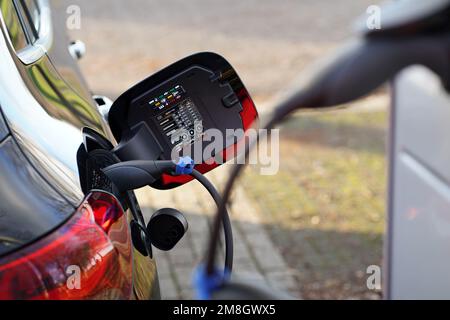 Charging an electric car. In the background is the plug connected to the car. The plug that is connected to the charging station is blurred. Stock Photo