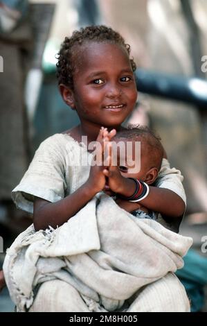 A Somali girl holding an infant waits to be examined by a Navy corpsman. Combat Service Support Detachment 15 (CSSD-15) is conducting a medical civic action program during the multinational relief effort Operation Restore Hope. Subject Operation/Series: RESTORE HOPE Base: Mogadishu Country: Somalia (SOM)