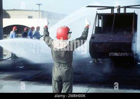 Students in the Damage Control 'A' School of the Naval Technical Training Center, Treasure Island, extinguish a fire which was engulfing a helicopter mock-up on a simulated flight deck. Base: San Francisco State: California (CA) Country: United States Of America (USA) Stock Photo