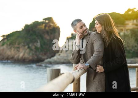 Romantic scene with a couple in love looking each other near the beach Stock Photo