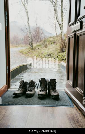 Man and woman's walking boots on a door mat. Stock Photo
