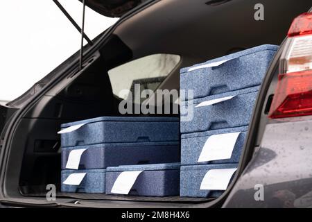 Hot meal packed in plastic and Styrofoam boxes in the back of a car to be delivered to the homes of seniors and disabled people Stock Photo