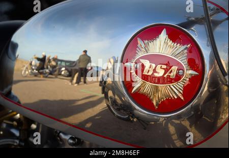 Chrome Petrol Tank Of A BSA Motorbike With Gold Star Emblem With A Reflection Of People And Mudeford Quay, UK Stock Photo