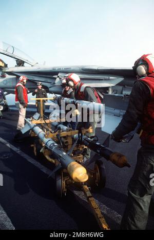 Aviation ordnancemen move an AIM-9 Sidewinder air-to-air missile from a weapons skid prior to mounting it on a Fighter Squadron 32 (VF-32) F-14A Tomcat aircraft on the aircraft carrier USS JOHN F. KENNEDY (CV-67). Country: Adriatic Sea Stock Photo