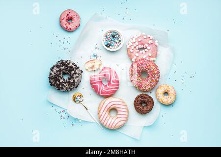 Parchment with different delicious donuts on blue background Stock Photo